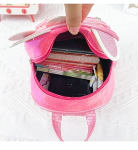 Pink pearlescent cat ear backpack showing inner capacity with phone and stationery