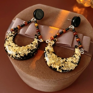 Detailed view of vintage crescent earrings with gold foil texture on a brown ribbon box