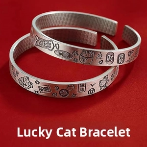 Detail view of silver cuff bracelets featuring lucky cat relief and Chinese characters