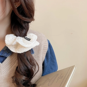 Detailed knit texture of white lace scrunchie with fashion label on long wavy hair