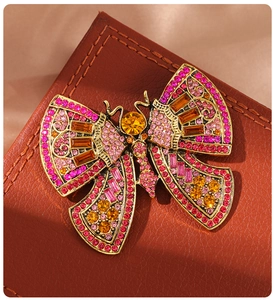 Macro detail of a vintage gold butterfly brooch with pink and yellow rhinestones