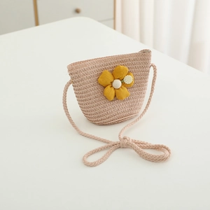 Detail einer Strohhandtasche für Kinder mit gelber Stoffblume und gewebtem Schultergurt