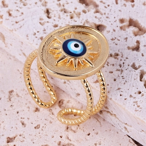 Macro shot of gold sun evil eye ring on pink stone texture focusing on enamel detail