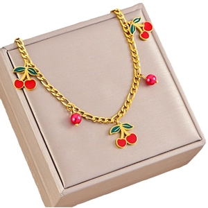 Golden Figaro chain necklace with red enamel cherry charms and red pearls on a jewelry box