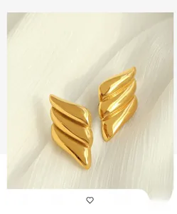 Macro shot of polished gold triangular earrings on a luxurious white satin background