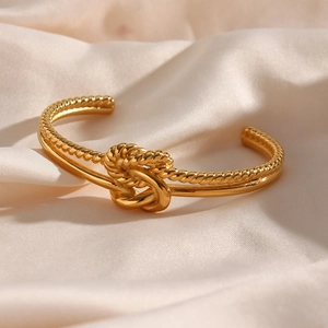 Macro detail of gold knot cuff bracelet with twisted rope texture and polished finish