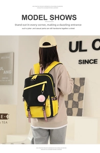 Detail view of a black and yellow color-block nylon backpack with a pink plush charm