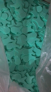 Detail view of bulk green silicone Y-shape eyelash brushes in a clear plastic storage bag