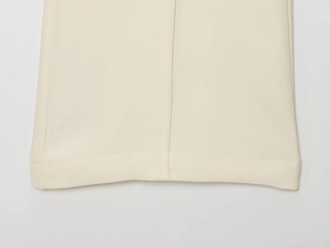 Détail du pantalon de costume avec coutures d'ourlet soignées et tissu crème de qualité
