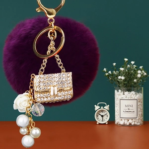 Detail showing purple pompom and crystal rhinestone purse keychain with pearls