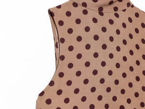 Detail view of the crew neck and sleeve tailoring on a brown polka dot sleeveless midi dress