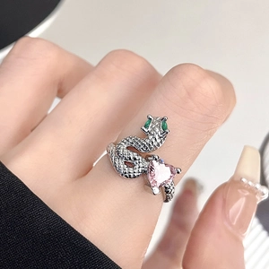 Dettaglio anello a serpente con zircone rosa a cuore e occhi di gemme verdi su argento