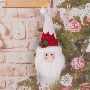 Knitted Santa Claus candy color ornament hanging on a Christmas tree against a brick wall