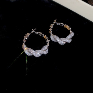 Detailed macro view of silver hoop earrings with twisted design and sparkling zircon pavé