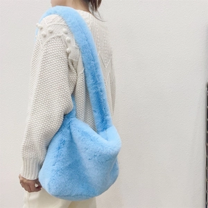 Detail of light blue faux fur shoulder bag with soft texture and wide strap on model