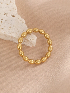 Macro shot of minimalist gold beaded ring with oval link design on textured fabric