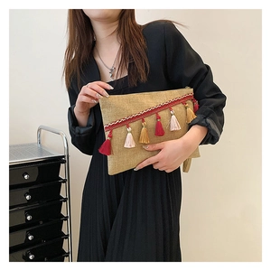 Close-up of bohemian envelope clutch featuring colorful tassels and woven linen fabric