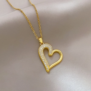 Macro shot of gold heart pendant with sparkling crystals on soft silk fabric