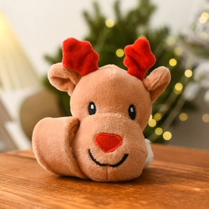 Close-up of reindeer plush toy with red antlers on wood surface with festive bokeh lights