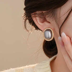 French vintage oval earrings with gray gemstone and gold base worn by model