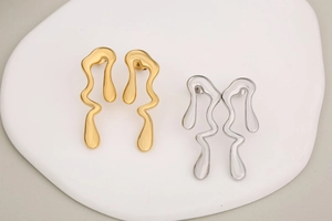 Détail macro de boucles d'oreilles métalliques irrégulières en finitions or et argent