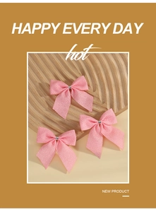 Three pink linen Christmas bows on a textured wooden tray with a festive design