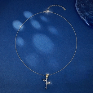 Detailed close-up of a dual-tone S925 silver rose necklace on a dark blue background