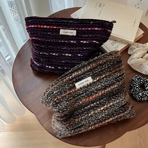Bohemian wool tweed makeup pouch with texture and brand logo in a cozy home setting