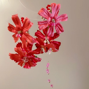 Macro shot of red fabric flower earrings with crystal beads and long tassels