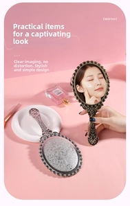 Close-up of vintage handheld mirrors with ornate floral relief on a soft pink background