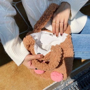 Detail view of the soft teddy plush tote bag featuring pink pom-poms and magnetic closure
