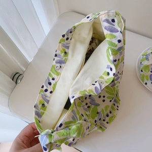 Detail view of cotton tote bag with purple leaf print, white lining and magnetic metal clasp