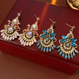Detail of vintage gold earrings with colorful crystals on a dark red wooden box