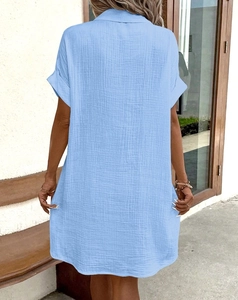 Back view of a loose light blue short sleeve shirt dress with wrinkled cotton texture