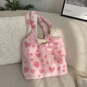 Close-up of pink fuzzy tote bag with heart patterns on a soft beige sofa