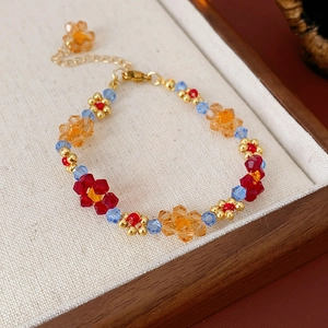Détail macro du collier de fleurs perlées colorées avec chaîne dorée sur plateau en bois