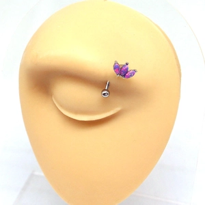 Detail shot of a silver eyebrow piercing featuring three pink opal stones in a crown setting