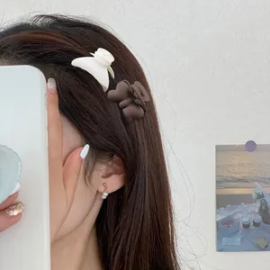 Matte flower and heart hair claws shown on brown hair with a cozy lifestyle background