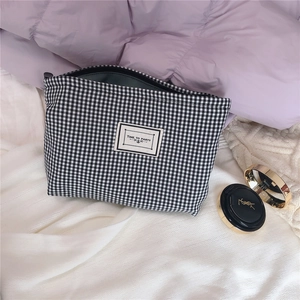Detail of a black and white checkered canvas makeup bag with Time to Party label