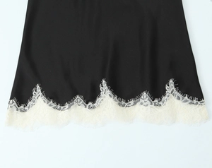 Close-up of black satin fabric top featuring elegant cream eyelash lace hem details