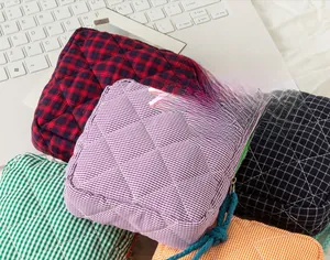 Detailed stack of colorful quilted plaid cosmetic bags for large capacity travel storage