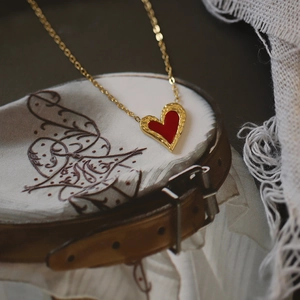 Detail of red heart necklace pendant with textured gold edge and fine titanium chain