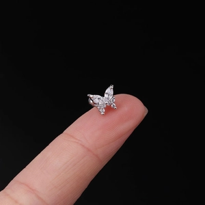 Macro view of tiny butterfly cartilage earring with cubic zirconia on a fingertip