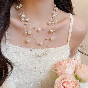 Detail of layered pearl necklace with gold chain worn by a model with a pink rose