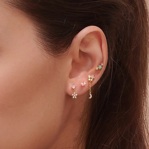 Close-up of assorted gold ear studs with colorful gems on ear cartilage