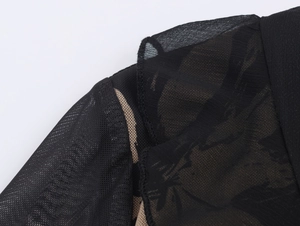 Close-up of black sheer mesh fabric detailing the fine texture and sleeve craftsmanship