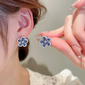 Close-up of vintage blue zircon flower earrings worn by a model to show detail