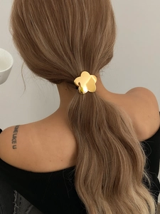Rear view of gold flower-shaped hair clip worn on a blonde ponytail for elegant styling