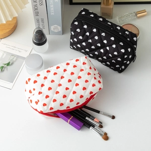Quilted heart pattern makeup bags in black and white styles on a stylish desk