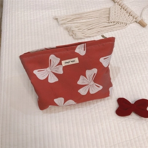 Detail of red canvas makeup bag with white bow pattern and simple wish textile label